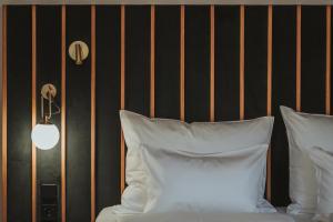 een bed met witte kussens naast een zwarte muur bij Arthotel Lasserhaus - adults only in Brixen