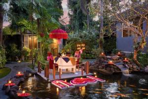 um jardim com uma mesa e cadeiras num lago em Tonys Villas & Resort Seminyak - Bali em Seminyak