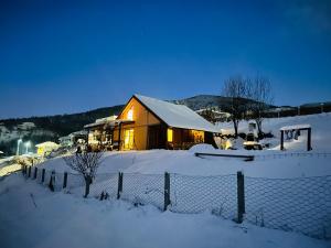 a house covered in snow in front of a fence at Log cabin 