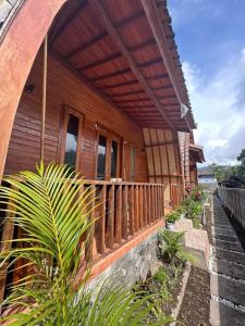 une maison en bois avec une terrasse couverte et quelques plantes dans l'établissement Volcano Cabins, à Kubupenlokan