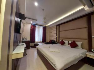 1 dormitorio con 1 cama blanca grande con almohadas rojas en New Gitanjali Hotel, New Digha, en Digha