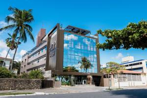 um edifício de vidro alto com árvores em frente em HCM - Hotel Corais de Manaira em João Pessoa