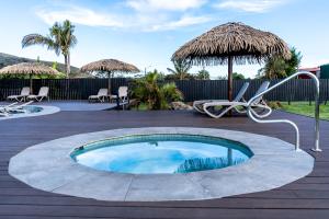 a small swimming pool with chairs and umbrellas at Hotel Ohana Rapa Nui in Hanga Roa