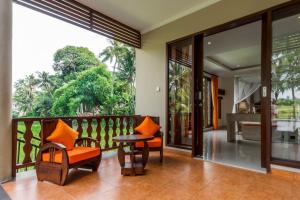 Camera dotata di balcone con tavolo e sedie arancioni. di Gefecon Villa Ubud ad Ubud