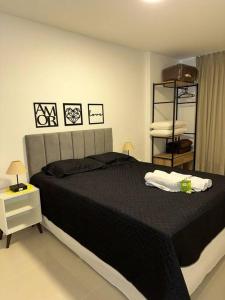 a bedroom with a large bed with a black blanket at Loft 511 Super Aconchegante no Coração de Teresópolis in Teresópolis