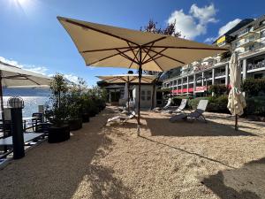 patio z krzesłami i parasolem obok budynku w obiekcie Seehotel Riviera at Lake Lucerne w mieście Gersau