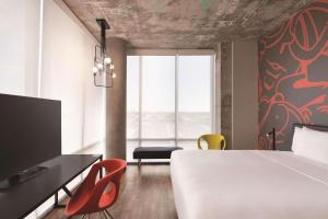 um quarto com uma cama, uma secretária e cadeiras em Radisson RED Miami Airport em Miami