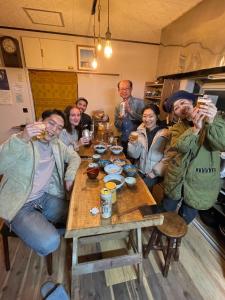 un grupo de personas sentadas en una mesa bebiendo cerveza en ゲストハウス千倉のおへそ en Chikura