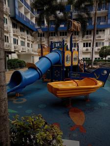 um escorrega azul num parque infantil em frente a um edifício em King of kings at SEA RESIDENCES em Manila