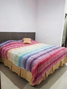 Una cama con una manta de colores encima. en Villa Mawar Bumi Citeko en Bogor