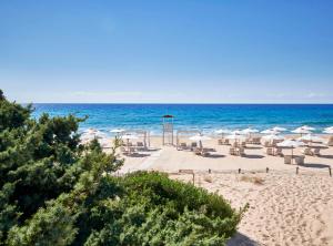 plaża z leżakami i parasolami oraz ocean w obiekcie Baia Di Chia Resort Sardinia, Curio Collection By Hilton w mieście Chia