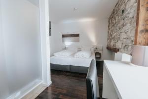 a bedroom with a bed and a stone wall at Design Hotel & Restaurant Löwen in Ulm