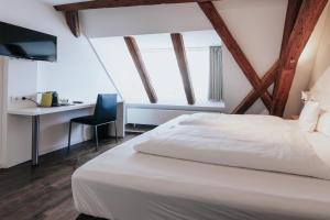 a bedroom with a white bed and a desk at Design Hotel & Restaurant Löwen in Ulm