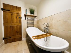 baño con bañera blanca y puerta de madera en 1 Apse Castle Cottage - Pet Friendly Cottage in Shanklin en Shanklin