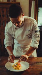 un hombre en una cocina preparando un plato de comida en Le Charaban en Aosta