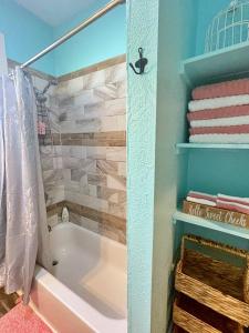 a bathroom with a tub and some towels and a shower at The Poolside Bungalow in Galveston