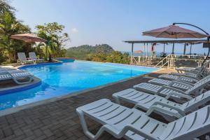 una piscina con sedie a sdraio e ombrelloni di El Faro Containers Beach Hotel a Manuel Antonio