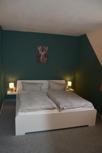 a bedroom with a bed with a green wall at Gasthaus B r o c k e n h e x e in Elbingerode