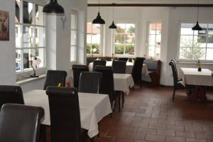 a dining room with tables and chairs and windows at Gasthaus B r o c k e n h e x e in Elbingerode