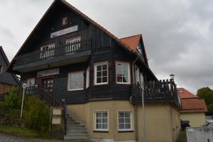 a house with a black roof and a balcony at Gasthaus B r o c k e n h e x e in Elbingerode