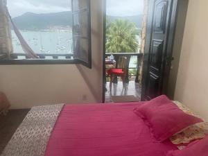 een slaapkamer met een roze bed en een raam met uitzicht bij Mansão Espetacular Angra in Angra dos Reis