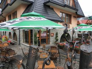 eine Terrasse mit Stühlen und Sonnenschirmen vor einem Gebäude in der Unterkunft Brzoza w centrum Zakopanego in Zakopane