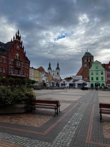 uma praça da cidade com dois bancos e edifícios em Pokoje Gościnne FABIO em Chojnice