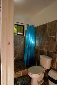 uma casa de banho com um WC e uma cortina de chuveiro azul em Hotel Swell Pavones em Pavones