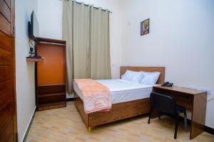 een slaapkamer met een bed, een bureau en een computer bij Paco Lodge in Dodoma