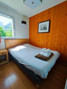 ein Schlafzimmer mit einem Bett mit einer Holzwand in der Unterkunft Résidence Val de Roland in Luz-Saint-Sauveur