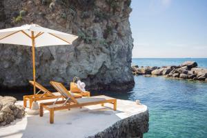 2 sedie a sdraio e un ombrellone in spiaggia di Pagoda Lifestyle Hotel a Ischia