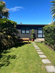 un banco sentado en el césped frente a una casa en Evolve Bach, en Whitianga