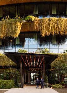 フンシャルにあるThe Reserve - The Leading Hotels of the World - Savoy Signatureの吊り植物の建物の前に立つ二人