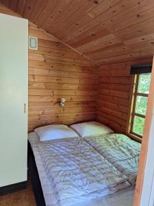 1 dormitorio con 1 cama en una cabaña de madera en Lyngholt Familiecamping, en Allinge