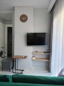 sala de estar con TV de pantalla plana en la pared en The Yacht apartments, en Alanya