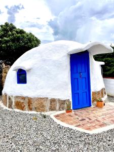 une petite maison en forme de dôme avec une porte bleue dans l'établissement Bahareque glamping, à Barichara