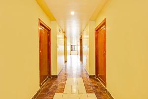 un couloir avec un long couloir et des portes en bois dans l'établissement Hotel O Gajuwaka Near kurmanpalem formerly SBT, à Visakhapatnam