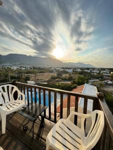 2 sillas y una mesa en un balcón con vistas a la puesta de sol en The Horse Farm Hotel en Kyrenia