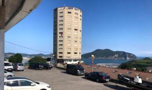 a parking lot with cars parked in front of a tall building at La Torre, vistas a la bahía in Laredo