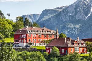 een groot rood huis voor een berg bij Tyssedal Hotel in Tyssedal