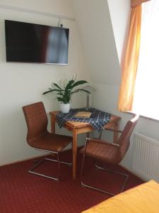 Habitación con mesa, 2 sillas y TV. en Gästehaus Loschwitz en Dresden