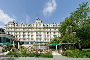 un gran edificio blanco con una bandera encima en Hotel Eden Palace au Lac en Montreux