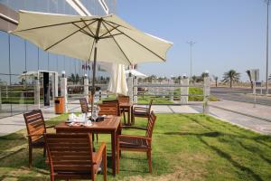 una mesa y sillas con una sombrilla en la hierba en Raoum Inn Khafji Corniche en Al Khafji