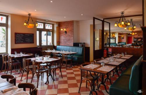 un restaurante con mesas y sillas en una habitación en Hotel De Normandie en Arromanches-les-Bains