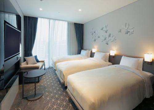 um quarto de hotel com três camas e uma televisão de ecrã plano em Hotel Gracery Seoul em Seul