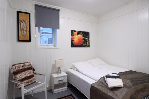 een kleine slaapkamer met een bed en een stoel bij Kristina Apartment & Alma House in Andenes