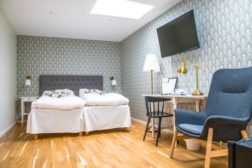 een slaapkamer met 2 bedden, een bureau en een televisie bij Lindesbergs Stadshotell in Lindesberg