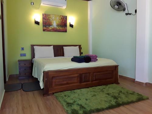 um quarto com uma cama com uma parede verde em Karl Holiday Bungalow em Kalutara