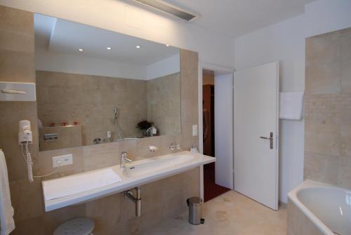 a bathroom with a sink and a large mirror at Hotel Schweizerhof in Engelberg