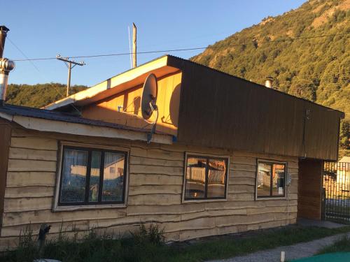 una casa de madera con una montaña en el fondo en Puesto Cánogas Hostal en Villa O'Higgins